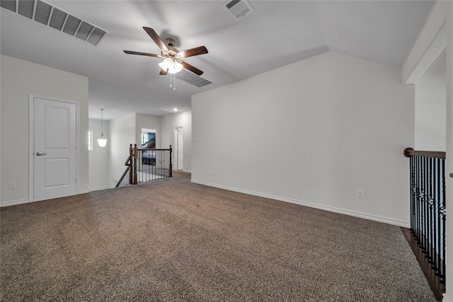 unfurnished living room with baseboards, dark colored carpet, visible vents, and a ceiling fan