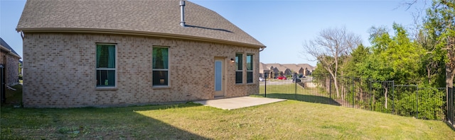 rear view of house featuring brick siding, a yard, roof with shingles, and fence