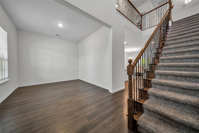 staircase featuring wood finished floors, visible vents, baseboards, and an inviting chandelier