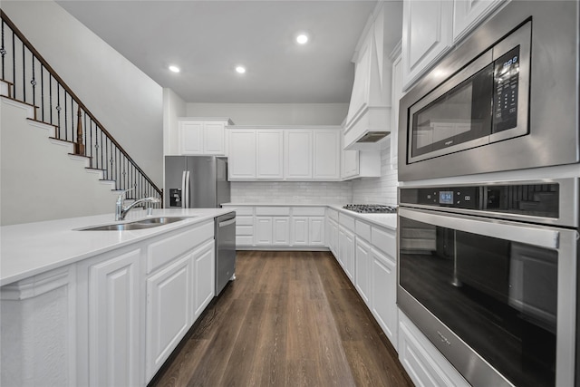 kitchen with stainless steel appliances, a sink, dark wood finished floors, decorative backsplash, and light countertops