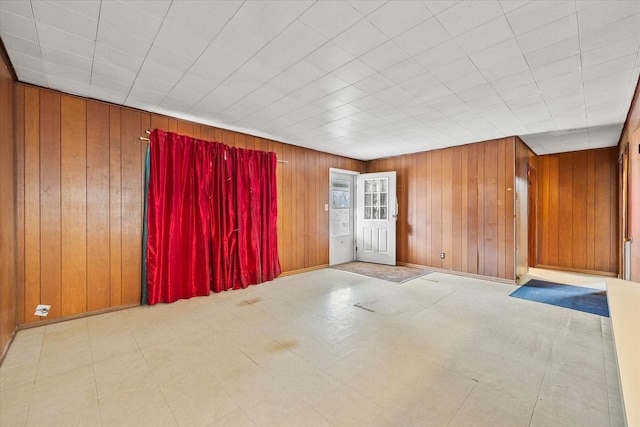 spare room with tile patterned floors and wooden walls