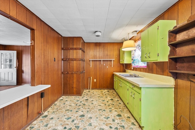 kitchen with open shelves, a sink, wooden walls, light countertops, and green cabinetry