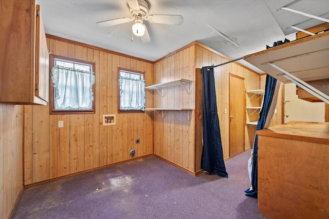 additional living space with baseboards, wood walls, ceiling fan, and carpet flooring