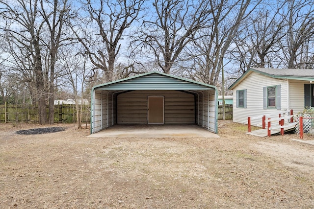 garage featuring a carport, driveway, and fence