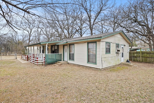 rear view of house with fence, covered porch, and cooling unit