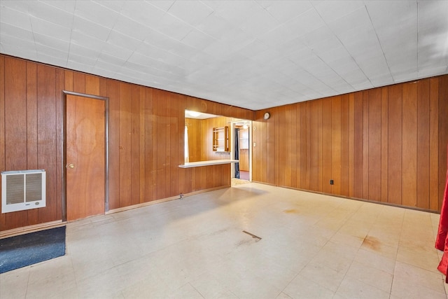 unfurnished living room with tile patterned floors, heating unit, and wood walls