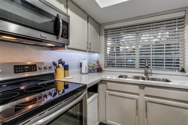 2535 Wedglea Dr Unit 114, Dallas, TX 75211 - kitchen with light stone counters, stainless steel appliances, a sink, decorative backsplash, and white cabinetry