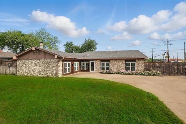 rear view of property featuring a chimney, a lawn, fence, a patio, and stone siding