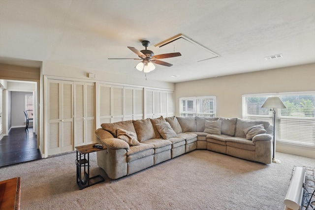 living room with ceiling fan, attic access, carpet flooring, and visible vents