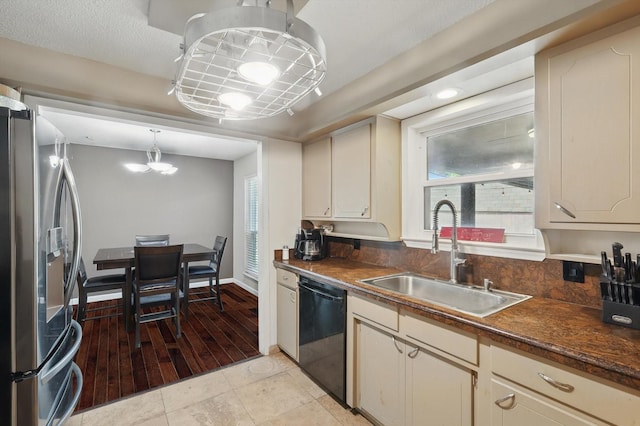 kitchen featuring a sink, dark countertops, stainless steel refrigerator with ice dispenser, and dishwasher