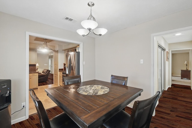dining space with visible vents, wood finished floors, and a chandelier