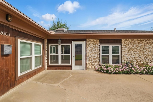 entrance to property with a patio and stone siding