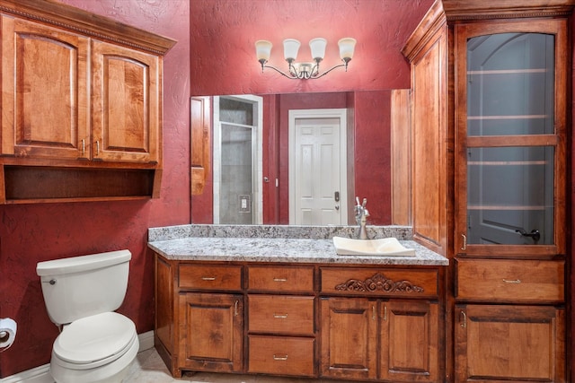 bathroom with a textured wall, vanity, a shower stall, and toilet