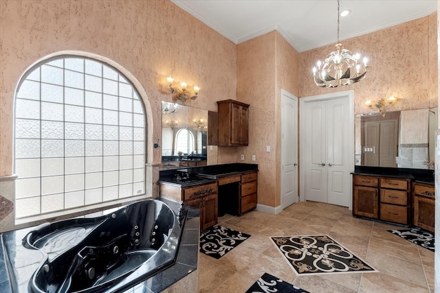 bathroom featuring baseboards, a notable chandelier, a whirlpool tub, vanity, and ornamental molding