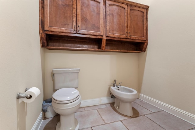 half bath with a bidet, tile patterned flooring, toilet, and baseboards