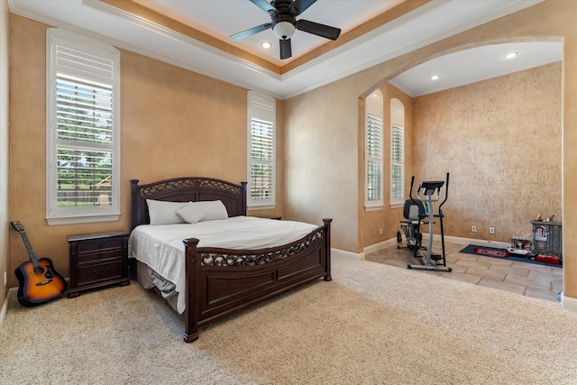 bedroom with arched walkways, baseboards, ornamental molding, carpet floors, and a raised ceiling