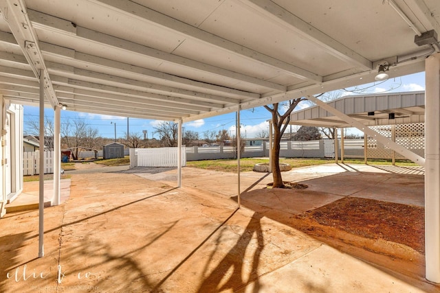 view of patio with fence, a storage unit, and an outbuilding