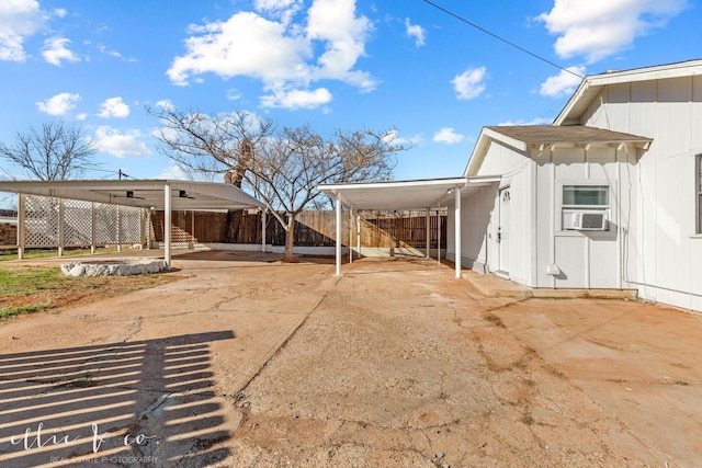 rear view of property featuring driveway, a carport, fence, cooling unit, and stairs