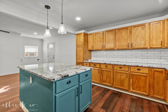 kitchen with dark wood finished floors, tasteful backsplash, crown molding, a kitchen island, and hanging light fixtures