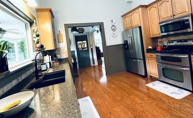 501 N Austin St, Comanche, TX 76442 - kitchen with stainless steel appliances, a sink, backsplash, wood finished floors, and dark stone counters
