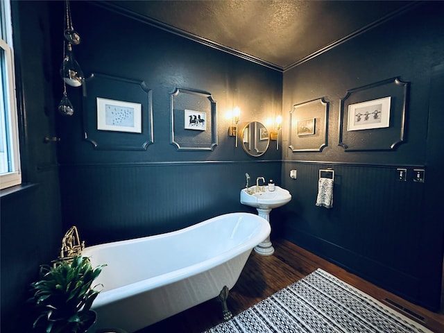 501 N Austin St, Comanche, TX 76442 - bathroom featuring a freestanding bath, wood finished floors, a textured ceiling, and wainscoting