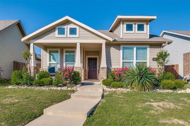craftsman-style house featuring brick siding, a porch, and a front yard