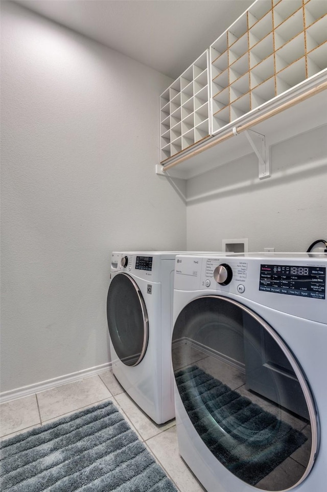 clothes washing area featuring baseboards, washer and dryer, laundry area, and light tile patterned flooring