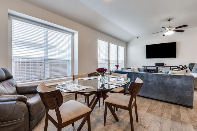 dining room featuring light wood finished floors, a ceiling fan, and lofted ceiling