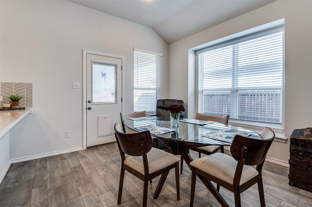 dining area featuring lofted ceiling, wood finished floors, and baseboards