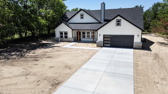 modern farmhouse with board and batten siding, an attached garage, driveway, and a shingled roof