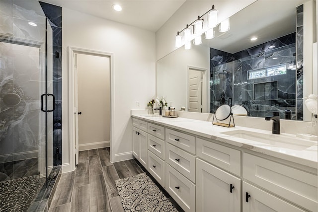 bathroom with double vanity, a sink, a marble finish shower, and wood finished floors