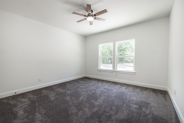 empty room featuring a ceiling fan, baseboards, and dark carpet