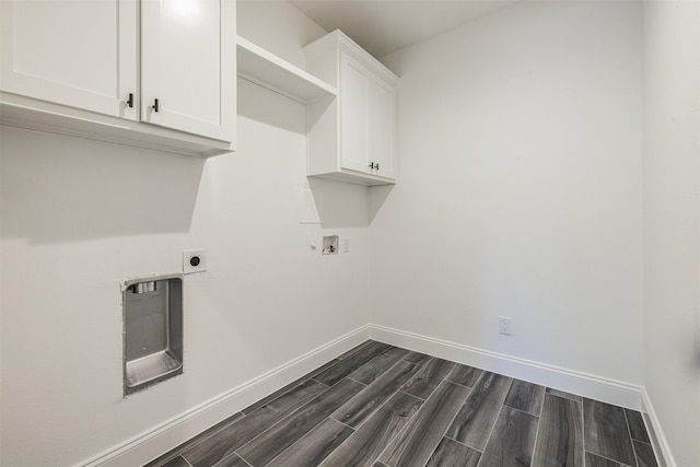 laundry room featuring cabinet space, hookup for an electric dryer, dark wood-style floors, and baseboards