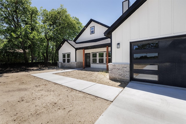 property entrance featuring board and batten siding, a patio, and roof with shingles