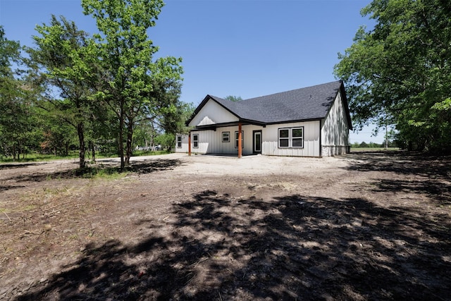 view of front of house with roof with shingles and dirt driveway