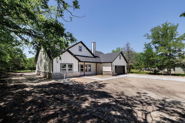 modern inspired farmhouse featuring a chimney, roof with shingles, brick siding, concrete driveway, and an attached garage