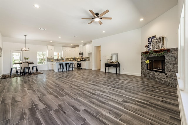 living room with recessed lighting, visible vents, ceiling fan with notable chandelier, and a fireplace