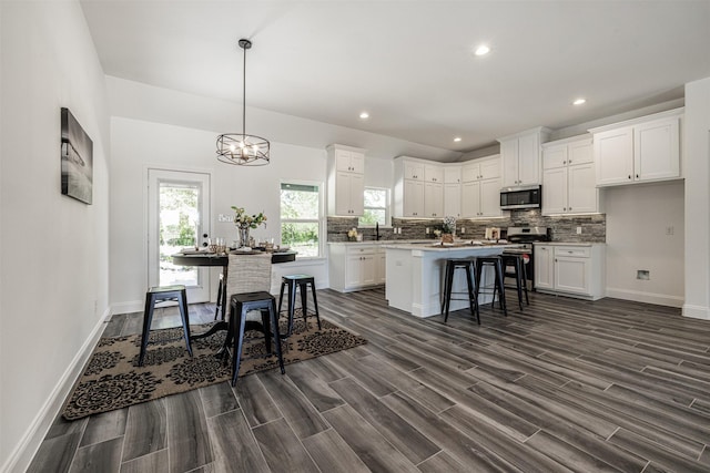 kitchen featuring dark wood-type flooring, white cabinets, appliances with stainless steel finishes, and a kitchen island