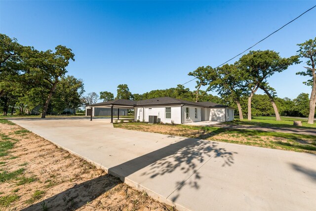 view of front of property with concrete driveway, a front lawn, and a carport