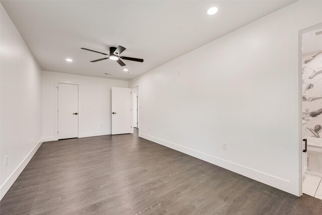 empty room featuring baseboards, a ceiling fan, and dark wood-style floors