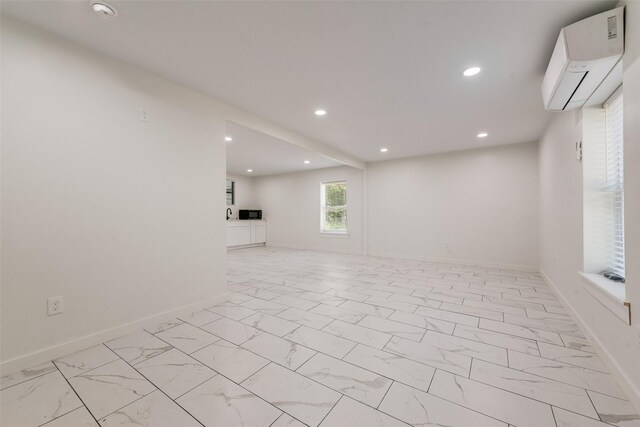 interior space with an AC wall unit, baseboards, marble finish floor, and recessed lighting