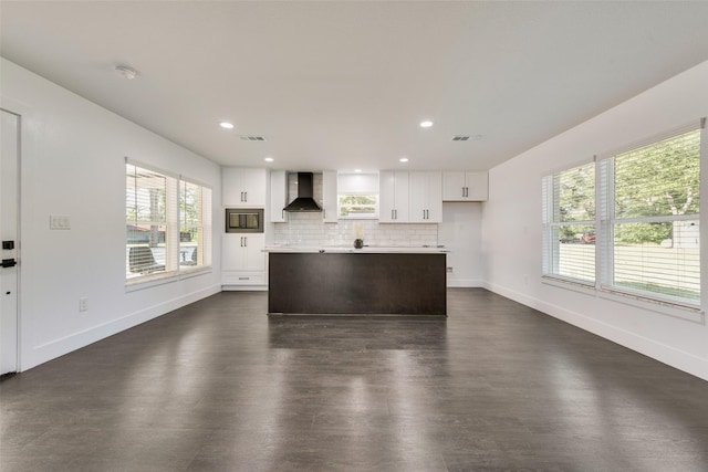 kitchen featuring white cabinets, light countertops, wall chimney range hood, baseboards, and decorative backsplash