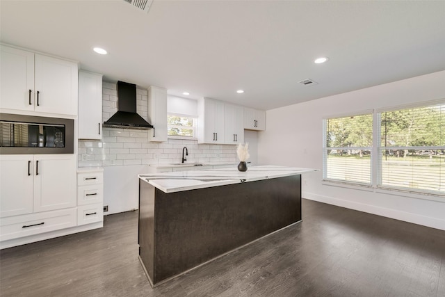 kitchen featuring backsplash, visible vents, dark wood-type flooring, black microwave, and wall chimney exhaust hood