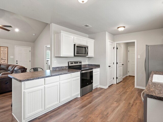 kitchen featuring dark countertops, stainless steel appliances, open floor plan, white cabinetry, and a ceiling fan