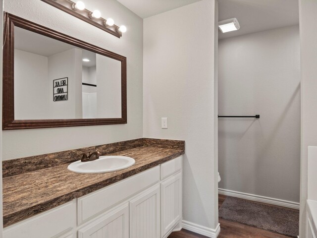 full bath with vanity, baseboards, and wood finished floors