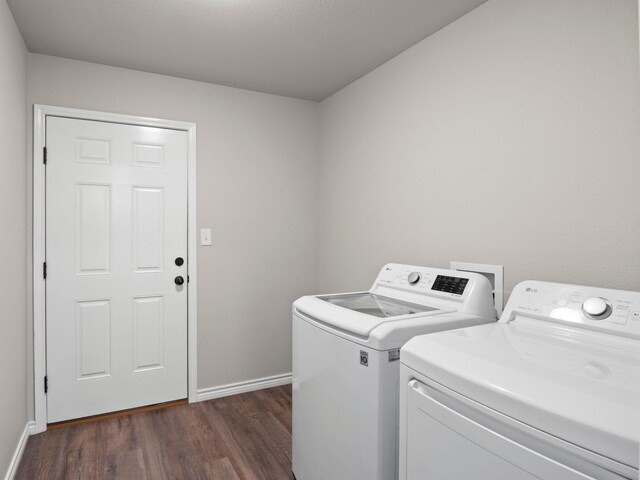 laundry area with laundry area, dark wood-style floors, washing machine and dryer, and baseboards