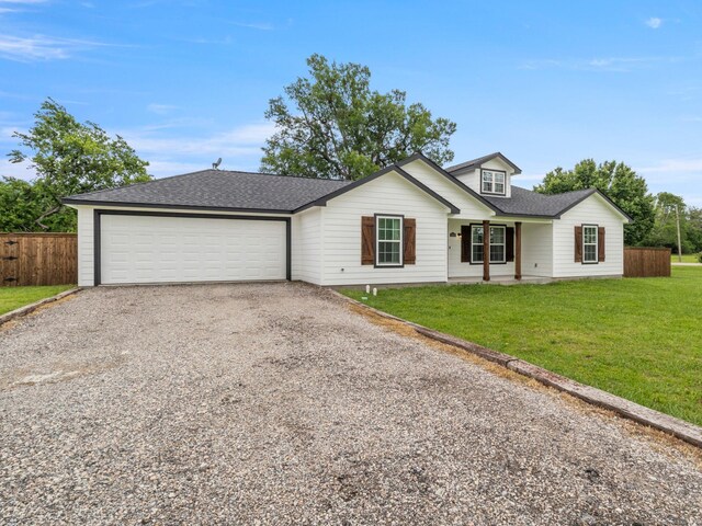 view of front of property featuring fence, roof with shingles, a garage, a front yard, and driveway