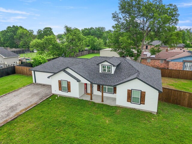 view of front of property with a front yard, a fenced backyard, roof with shingles, and gravel driveway