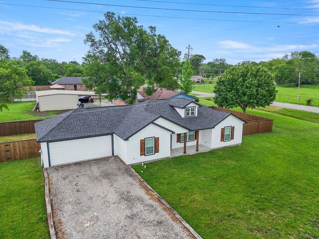 view of front of home featuring fence, a front lawn, roof with shingles, and a garage