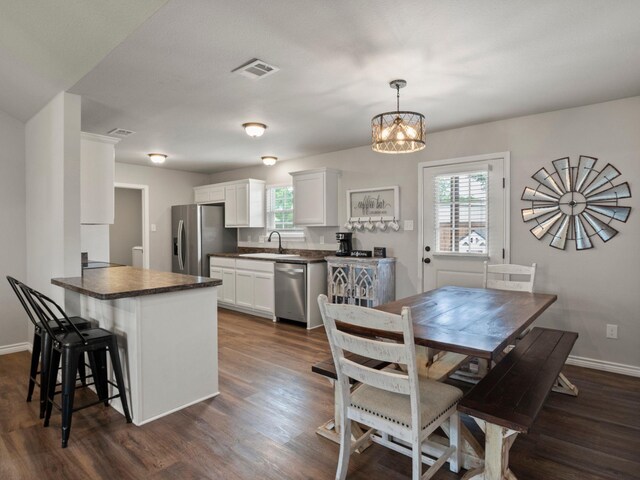 kitchen featuring white cabinets, dark countertops, a sink, stainless steel appliances, and dark wood-style floors